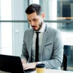 Profesional de TI trabajando en su computador en una oficina moderna, revisando la estrategia de backup de la empresa