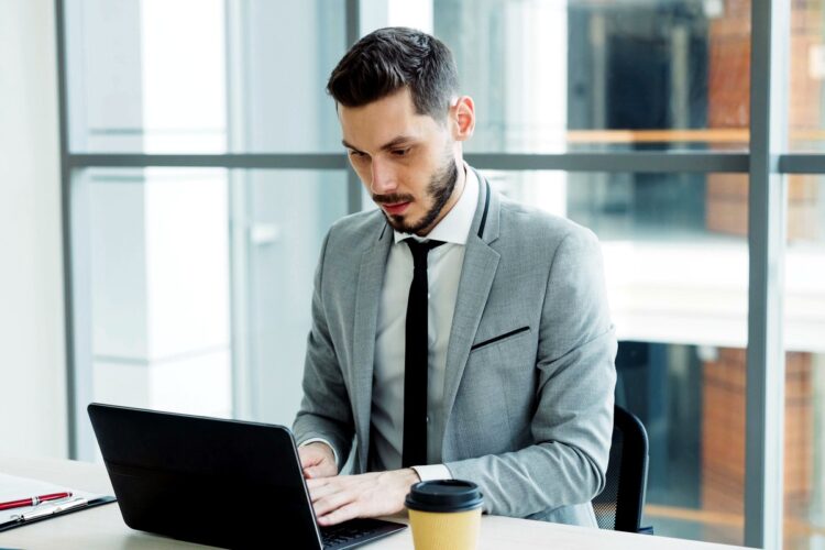 Profesional de TI trabajando en su computador en una oficina moderna, revisando la estrategia de backup de la empresa