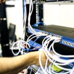 Técnico organizando y conectando cables de red en un switch empresarial dentro de un rack de infraestructura de red
