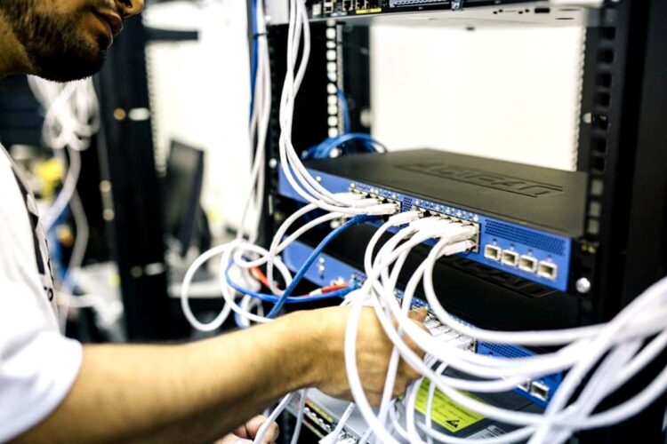 Técnico organizando y conectando cables de red en un switch empresarial dentro de un rack de infraestructura de red